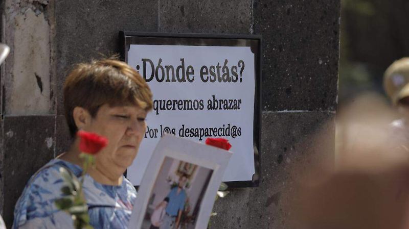 Mujer frente a un cartel por los desaparecidos